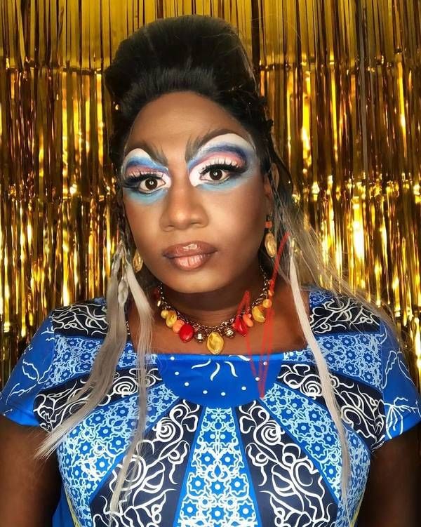 Yshee Black in a blue print outfit against gold tinsel