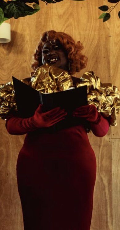 Yshee Black officiating a wedding in a red gown with gold sleeves